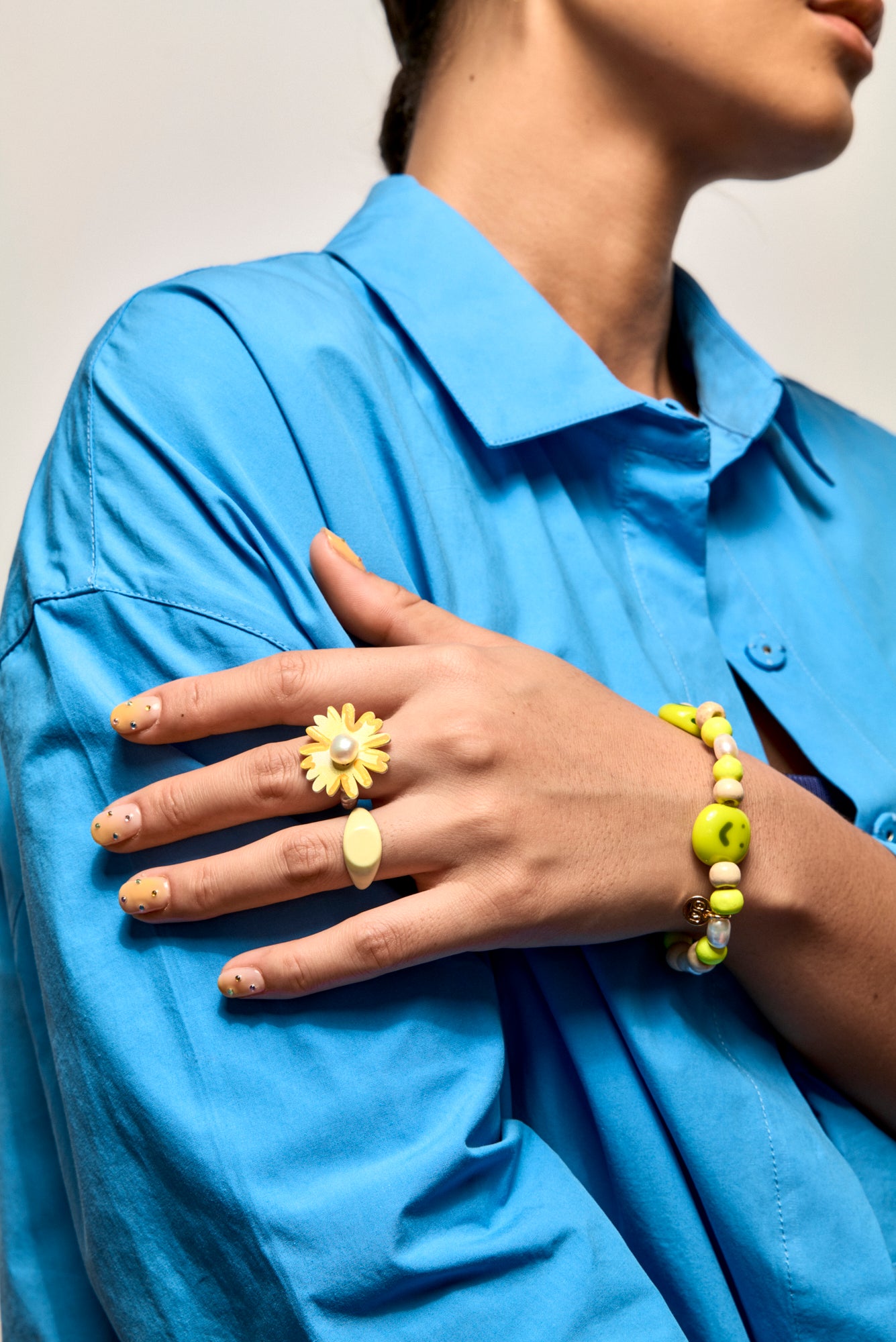 Model wears a blue shirt and a Bianca Mavrick Pearl Hand-painted Daisy Ring 